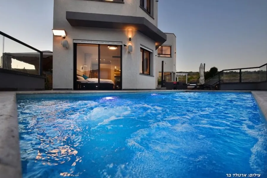 Dream House – the pool in the evening with house lights on